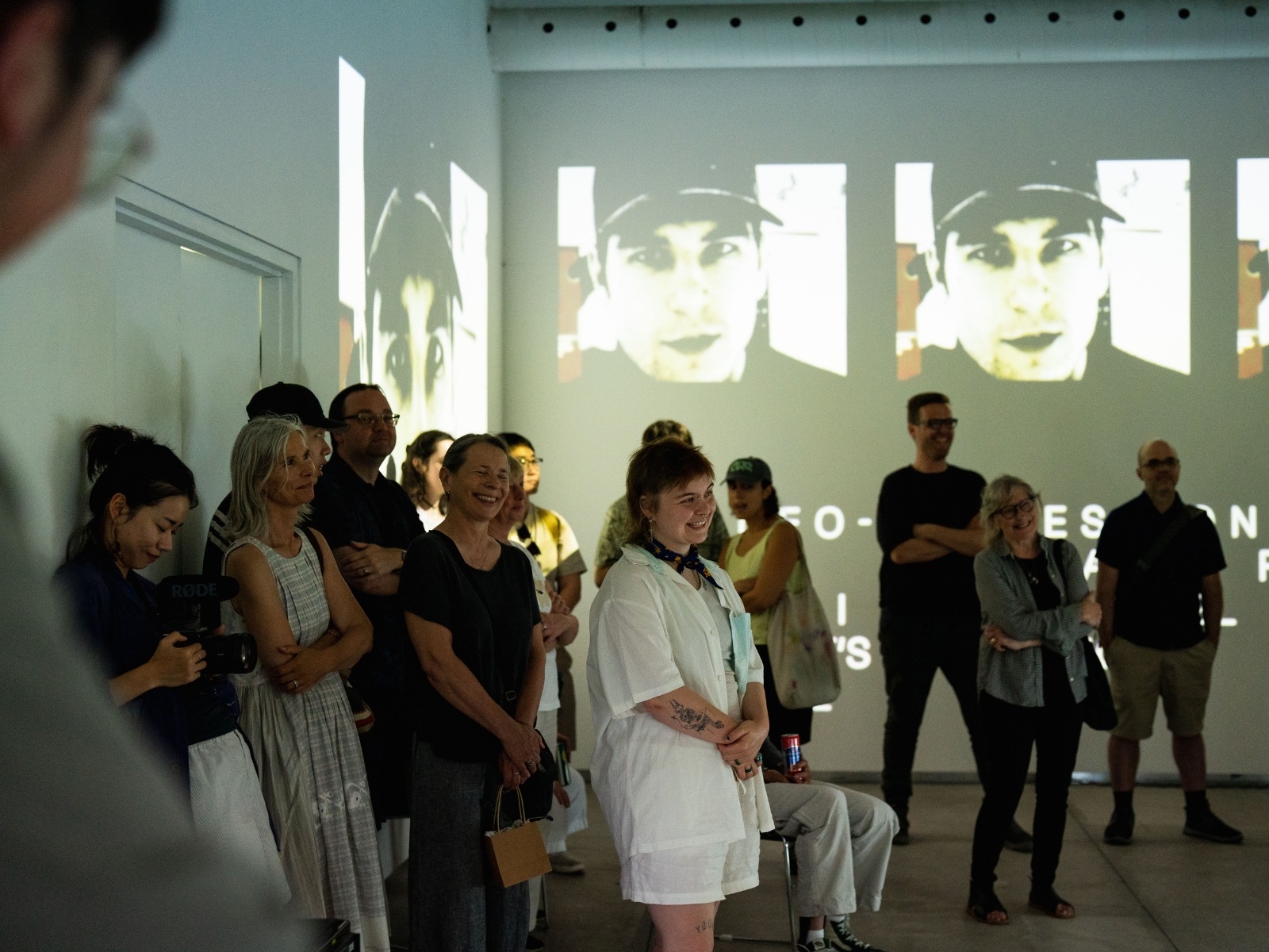 Visitors gathered in front of Tremblay’s exhibit pieces, which are shown off-screen, surrounded by projections of portraits.